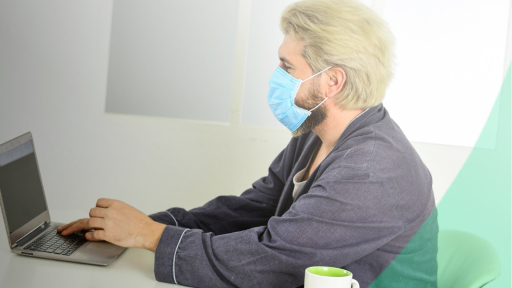 Мужчина в медицинской маске за ноутбуком